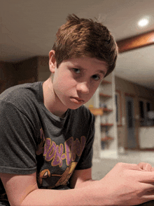 a young boy wearing a t-shirt that says ' snoopy ' on it looks at the camera