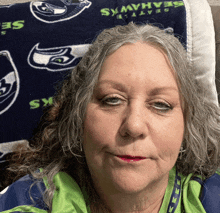 a woman laying on a bed with a seahawks pillow