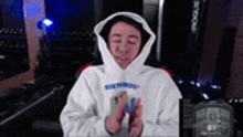 a young man wearing a white hoodie is holding a nintendo switch in his hands .