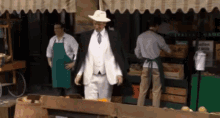 a man in a white hat stands in front of a grocery store with a sign that says italian grocery