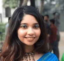 a close up of a woman 's face wearing a blue saree and a necklace .