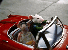 a couple of mice are driving a red car