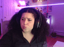 a girl with curly hair wearing headphones making a funny face