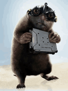 a cartoon mole is wearing a helmet and goggles and holding a laptop .