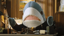 a stuffed shark is sitting at a desk wearing a suit .