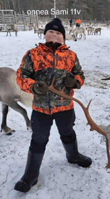 a young boy holding a reindeer antlers in a snowy field