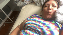 a woman in a colorful tie dye shirt laying on a bed