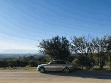 a silver car is parked on a dirt road