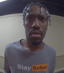 a man with dreadlocks wears a shirt that says stay sober