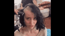 a woman is getting her hair shaved by a man with a razor .