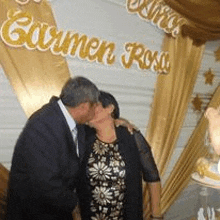 a man and woman are kissing in front of a sign that says carmen ross .