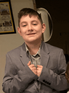 a young boy in a suit adjusts his sleeves