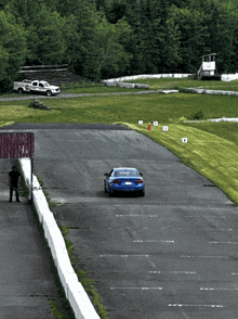 a blue car is driving down a race track with the number 4 on the side of the road