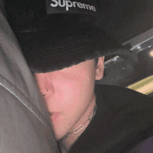 a man wearing a black hat with the word supreme on the front