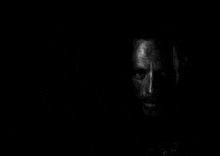 it is a black and white photo of a man 's face in the dark .