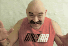 a man with a mustache wears a red nike air shirt