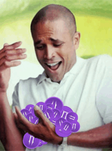 a man in a white shirt is holding a bunch of purple coins with the letter i on them