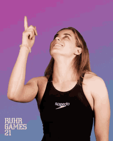 a woman wearing a black speedo tank top points upwards