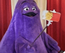 a purple mascot is taking a selfie with a mcdonald 's box of french fries