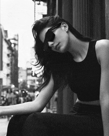 a black and white photo of a woman wearing sunglasses and a tank top