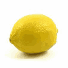 a single yellow lemon is sitting on a white surface .