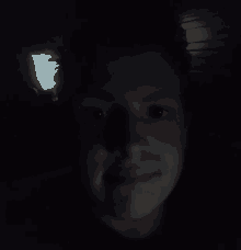 a close up of a person 's face in the dark with a light shining on it