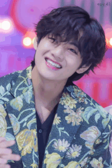 a close up of a person wearing a floral jacket and smiling