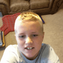 a young boy is taking a selfie in front of a brown couch