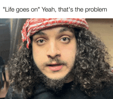 a man with curly hair and a beard is wearing a red and white scarf around his head and says " life goes on "