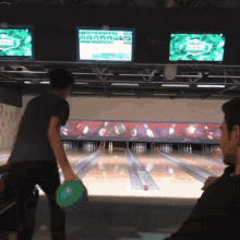 a man throws a bowling ball in a bowling alley with a scoreboard displaying a score of 2 to 1