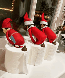 three elf on the shelf are sitting on toilet paper rolls