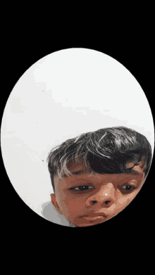 a young boy is looking at his reflection in a round mirror