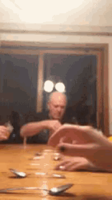 a blurry picture of a man sitting at a table with spoons