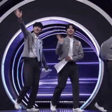 two men are dancing on a stage in front of a purple circle .