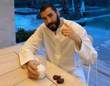 a man with a beard is sitting at a table with a glass of milk and dates