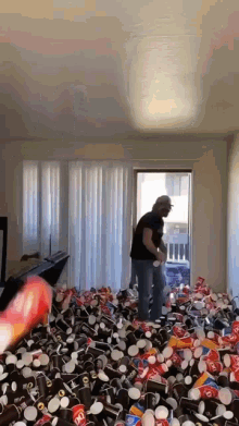 a man is standing in a room filled with lots of cups and cans including a bunch of dairy queen cups