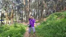 a man in a purple shirt is standing in the woods