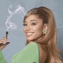 a woman in a green dress is smiling while smoking a cigar .