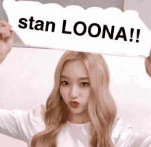 a woman holds a sign that says stan loona