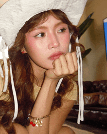 a woman wearing a white hat and a bracelet with the letter a on it