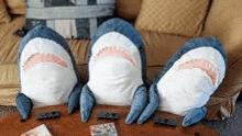 three stuffed sharks are sitting on a table next to each other .