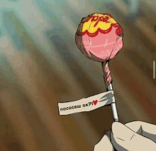 a person is holding a pink chupa chups lollipop with a russian label