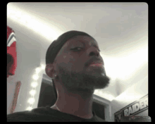 a man with a beard is standing in front of a raiders banner