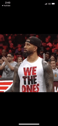 a man wearing a tank top that says we the ones is standing in front of a crowd .