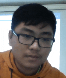 a close up of a young man wearing glasses and an orange hoodie .