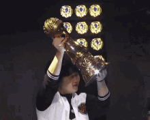 a person holding up a trophy with the letter m on the front