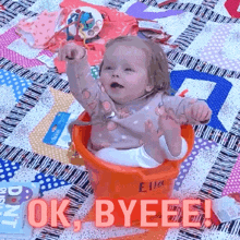 a baby is sitting in an orange bucket with the words ok byeee on the bottom