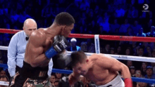 two men are fighting in a boxing ring with a referee watching .