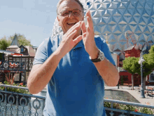 a man in a blue shirt is clapping his hands in front of a building that says ' eiffel tower '