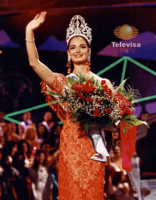 a woman wearing a crown is holding a bouquet of flowers in front of a televisa logo